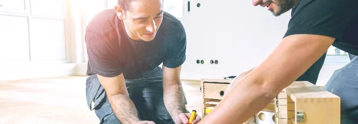 Zwei Personen bauen ein Schrank zusammen.